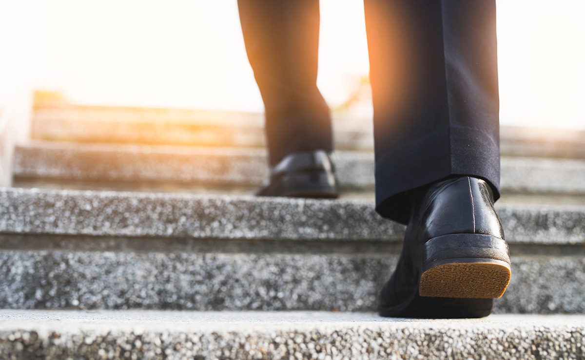 Image of a man walking up the stairs to achieve the goal